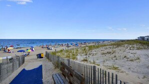Une plage avec une clôture en bois, des parasols et des gens.