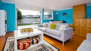 Uma sala de estar moderna com um sofá branco, uma mesa de centro e um armário de madeira.