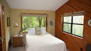 Une chambre à coucher avec un lit, une table de chevet, une lampe, une fenêtre et une porte.