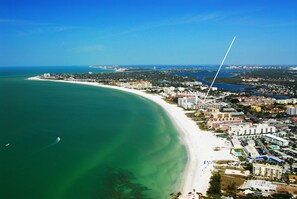 An aerial view of a coastal city with a wide beach, dense urban area, and a clear blue sky. - Beachfront Condo - 2-Bedroom - Luxury - Directly on Crescent Beach (Siesta Key)