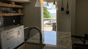 Een moderne keuken met een marmeren aanrechtblad, roestvrijstalen apparatuur en uitzicht op de omgeving.
