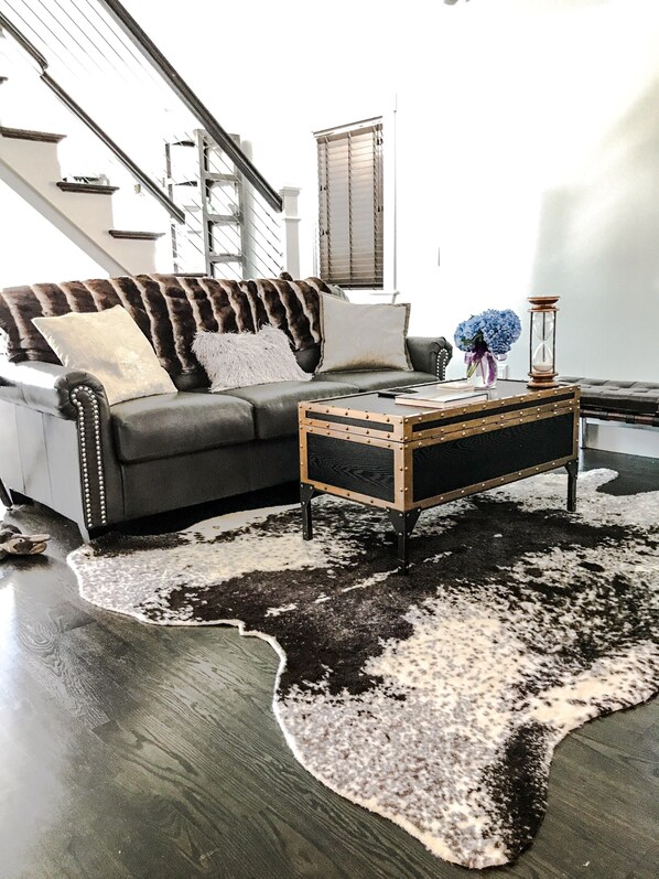 A living room with a dark grey sofa, a wooden coffee table, and a black and white cowhide rug.