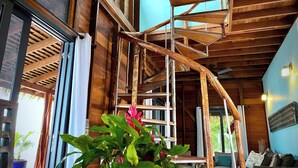 A wooden interior with a staircase, a sofa, and a table with a plant.