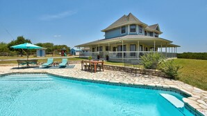A two-story house with a large front porch and a swimming pool.