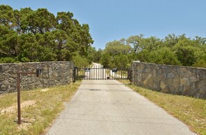 A gated entrance with a stone wall and a metal gate. - Prosit Ranch - 300 Acre Private Ranch w/360 Degree Views & Wrap-Around Porch (Wimberley)