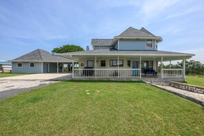 A two-story house with a covered porch and a stone foundation.