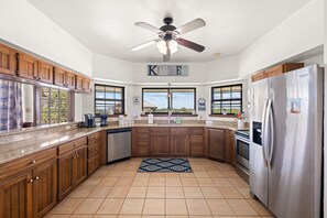 A kitchen with wooden cabinets, a stainless steel refrigerator, a dishwasher, and a ceiling fan.