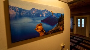 A painting of a mountain lake with a squirrel on a rock.