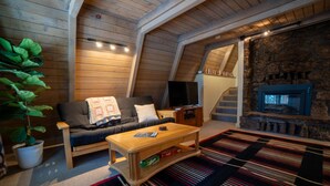 A cozy loft-style living room with a sofa, coffee table, and a stone fireplace.