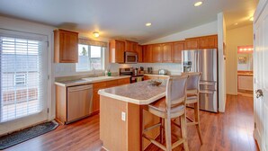 A spacious kitchen with wooden cabinets, stainless steel appliances, and a central island with bar stools.