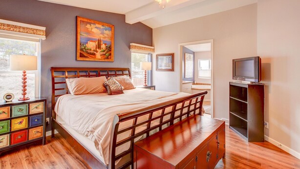 A bedroom with a bed, a nightstand, a TV stand, and a ceiling fan.