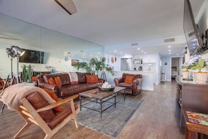 A modern living room with a leather sofa, a coffee table, and a dining area with a bar.