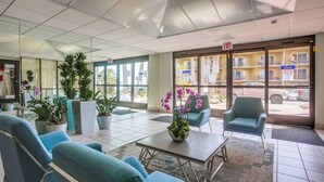 A hotel lobby with seating, a reception desk, and a view of the street outside.