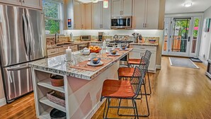 A modern kitchen with stainless steel appliances, a central island with seating, and a view to the outdoors.