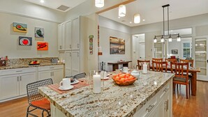 A modern kitchen with granite countertops, white cabinets, and a dining area with wooden chairs and a table.