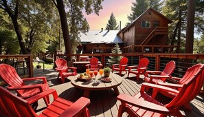 A wooden deck with red chairs and a table set for dining, overlooking a cabin with a metal roof. - Twain Harte Group Cabin: Sleeps 21+, Walk to Town, Lake Access, Pet-Friendly (Twain Harte)