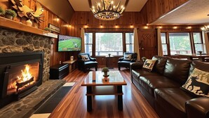A cozy living room with a stone fireplace, leather furniture, and a large window with a view of the outdoors.