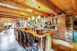 Una cocina amplia con armarios de madera, una isla grande con taburetes de bar y lámparas colgantes.