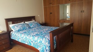 A bedroom with a wooden bed, a nightstand, a dresser, and a wardrobe. - Middleton Halleedays - Beach getaway (Middleton)