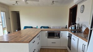 A modern kitchen with white cabinetry, a wooden countertop, and a built-in microwave. - Middleton Halleedays - Beach getaway (Middleton)