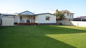 A single-story mobile home with a blue roof, a covered porch, and a fenced backyard. - Middleton Halleedays - Beach getaway (Middleton)