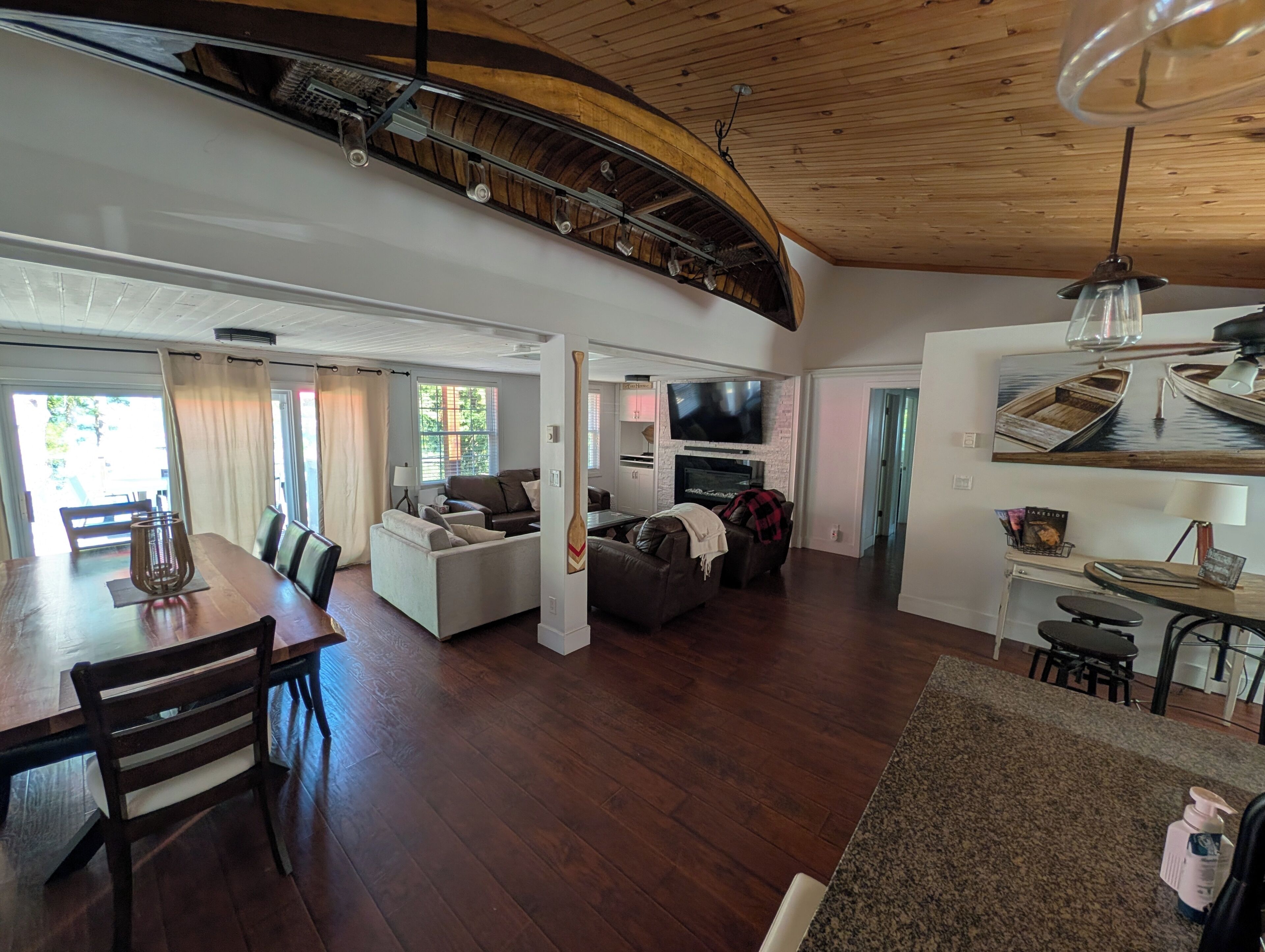Ein großzügiger Wohnbereich mit hohen Decken, Kamin, Fernseher und Essbereich mit Tisch und Stühlen.