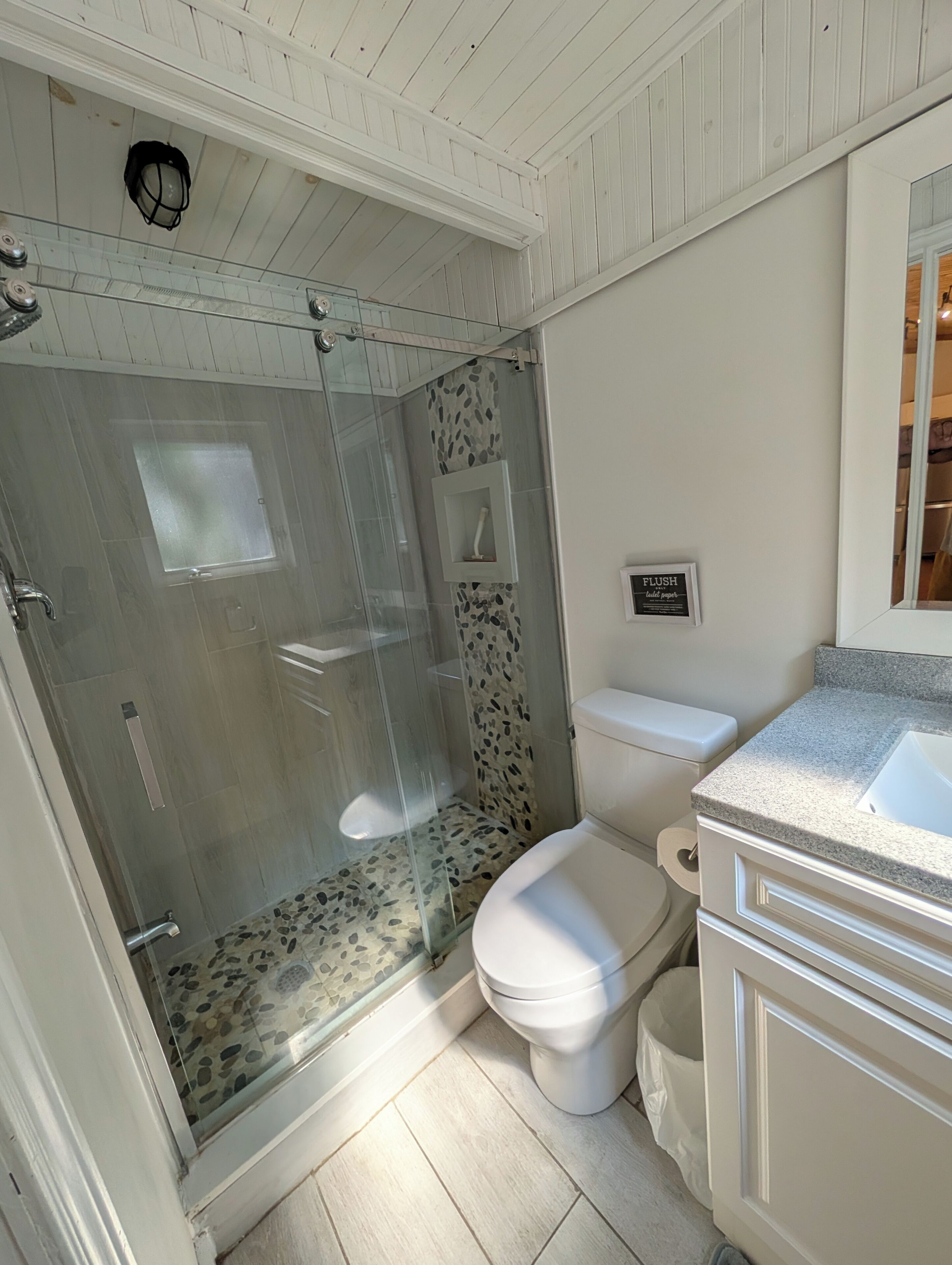 A bathroom with a glass-enclosed shower, a toilet, a sink, and a vanity.
