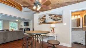 Una cocina moderna con techo de madera, un comedor con taburetes y un cuadro grande de barcos en la pared.