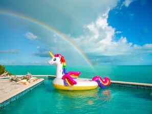 A pool with a unicorn float and a rainbow.