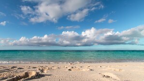 Une plage à l’eau turquoise et limpide, bordée d’un rivage sablonneux.