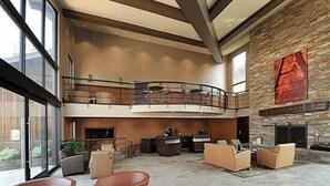 A spacious lobby with a stone fireplace, leather seating, and a balcony overlooking the area. - Centrally Located Studio Condo, minutes from Main St and Skiing! (Park City)