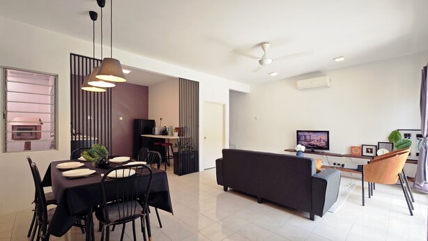 A modern living space with a dining area, kitchen, and a seating area with a TV.