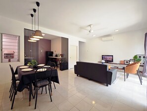 A modern living space with a dining area, kitchen, and a seating area with a TV.