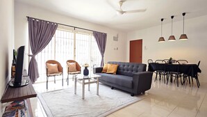 A modern living room with a sofa, armchairs, a coffee table, and a dining area with a table and chairs.