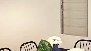 A dining table set for six with black chairs, a vase with white flowers, and a blue vase with green leaves.