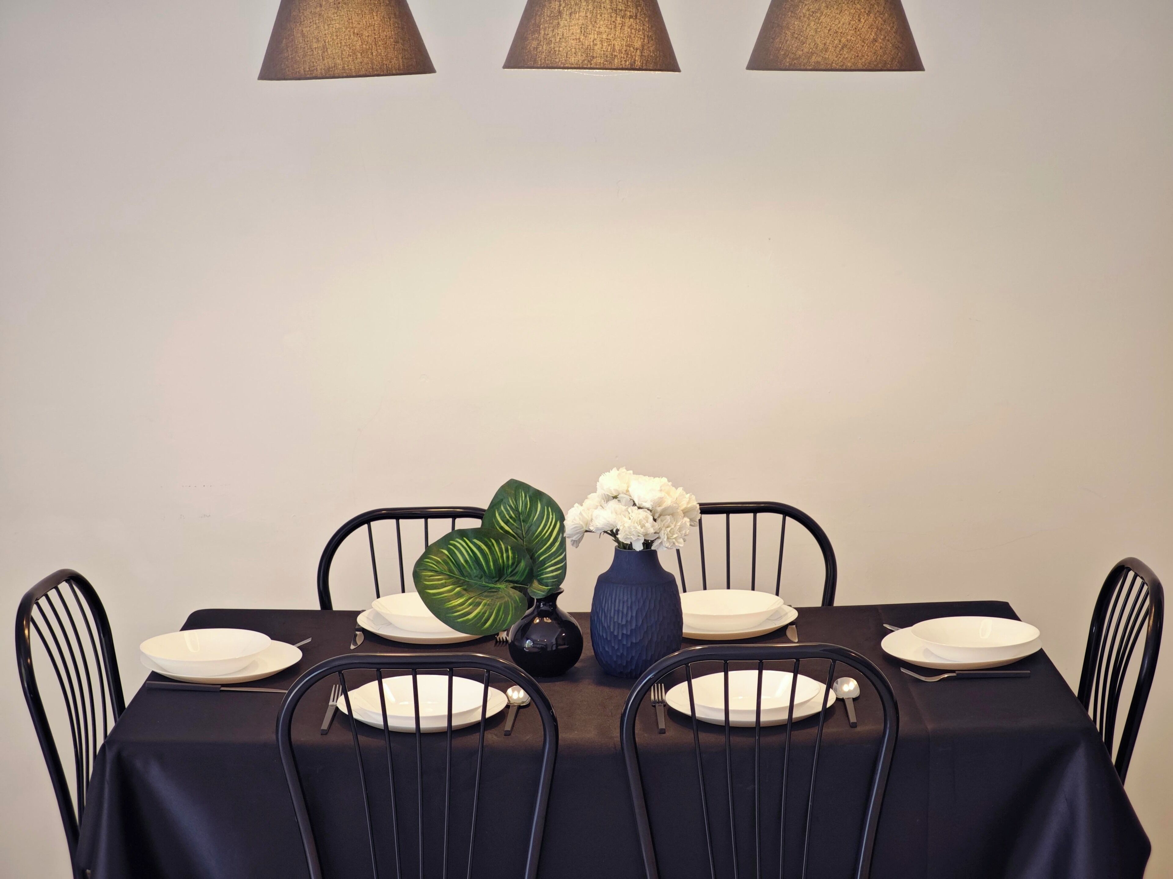 Ein Esstisch gedeckt mit Tellern, Besteck, einer Blumenvase und einem Blumentopf.