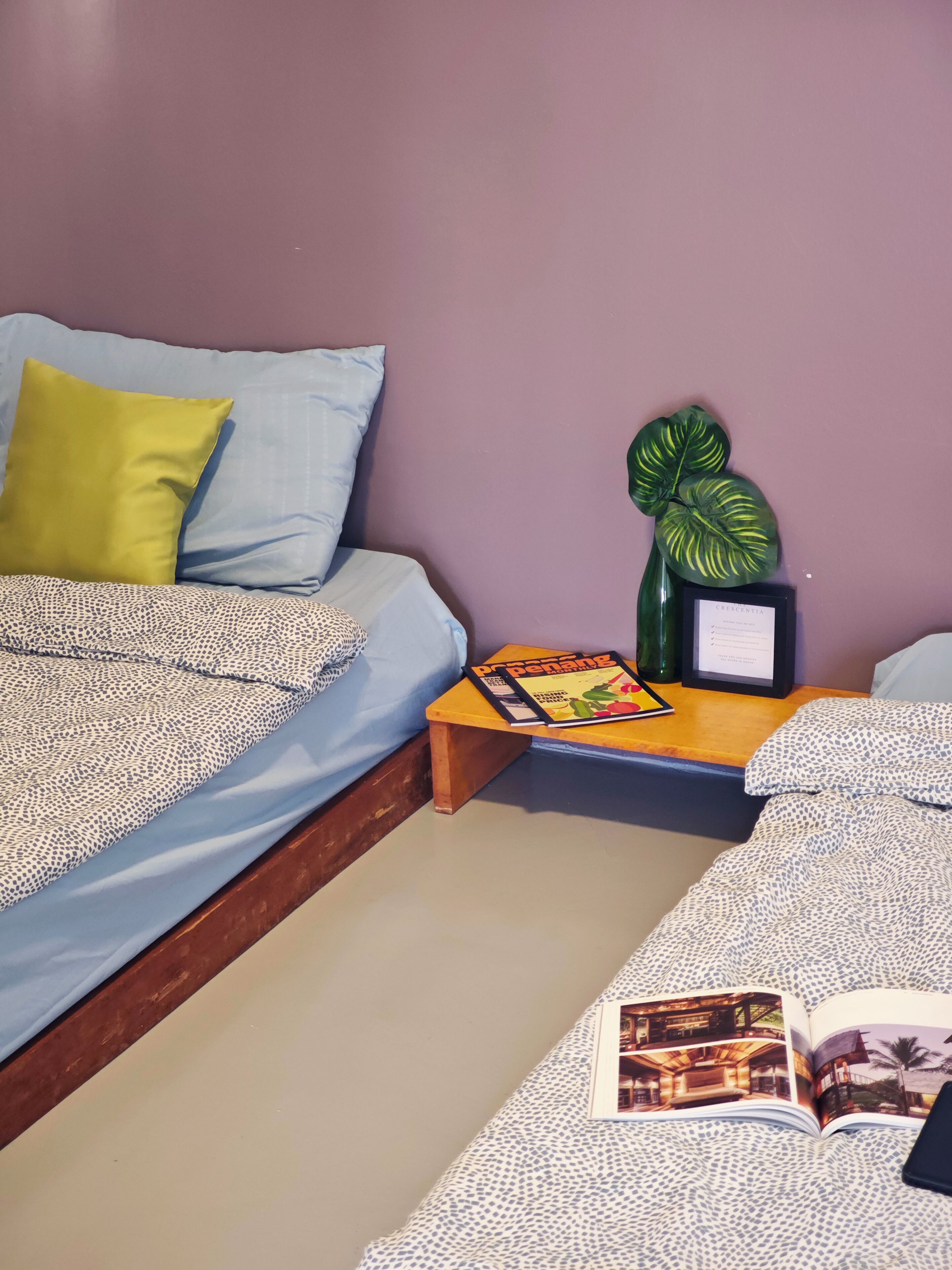 A bedroom with a bed, a nightstand, a framed certificate, and a magazine.