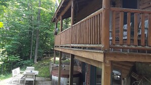 A wooden cabin with a deck, outdoor seating, and a fire pit. - A beautiful log cabin home on Lake Huron, amazing lake views, hot tub, game room (Cheboygan)