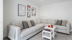 Una sala moderna con un sofá seccional gris, una mesa de centro blanca y obras de arte enmarcadas en la pared.
