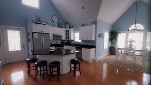 A kitchen with a central island, bar stools, and a dining area with a table and chairs.