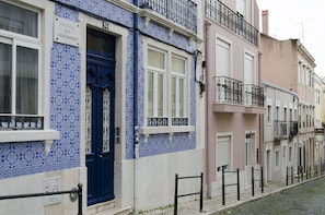 A row of buildings with blue and white patterned facades, a cobblestone street, and black metal railings.