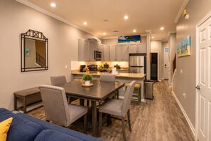 A modern kitchen with a central island, grey cabinetry, and stainless steel appliances.