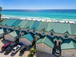 A beachfront hotel with multiple units, a parking area, and a view of the ocean.