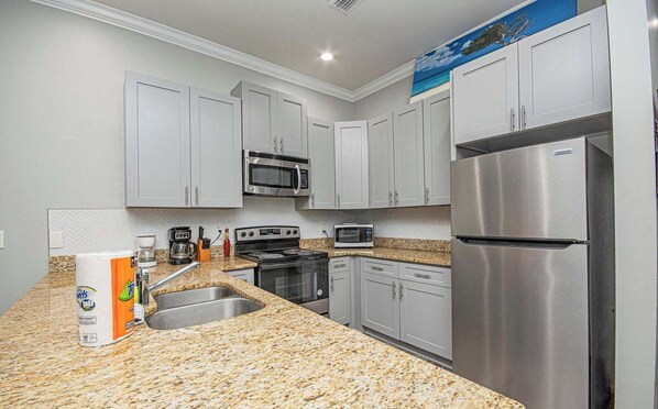 A kitchen with granite countertops, stainless steel appliances, and white cabinets.