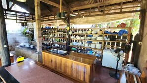 A rustic kitchen with a wooden counter, shelves with dishes, and a stone stove. - Amazing Villa With Gorgeous Private Beach (Puerto Princesa)