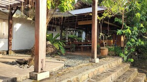 Un espace extérieur aménagé dans un style rustique, avec des marches en pierre, des tables en bois et des plantes en pot.