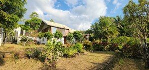 A house with a sloped roof, surrounded by a garden with various plants and trees.
