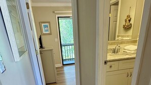 Pasillo que lleva a un baño con lavabo y espejo.