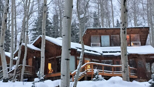 A wooden cabin surrounded by snow-covered trees.