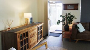 Un salon avec un meuble en bois, une lampe, une plante et un canapé.